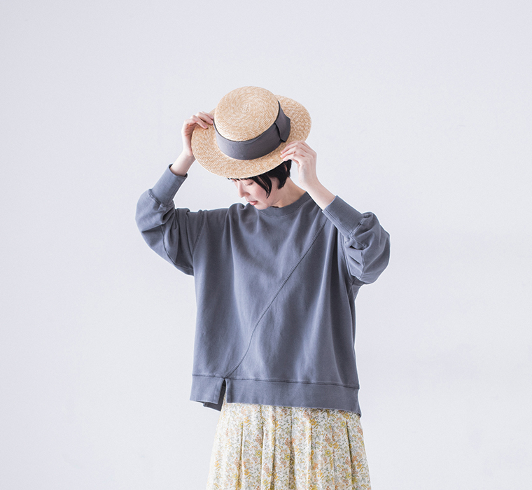 ピグメント裏毛斜め切り替えプルオーバー ブルーを着用したモデルの全身正面でストローハットと小花柄スカートを合わせたコーディネート