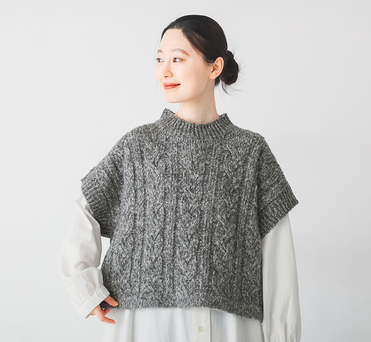 グレーのMIXメランジケーブルニットベストを白のシャツワンピースに重ねて着用している上半身のスタイリング