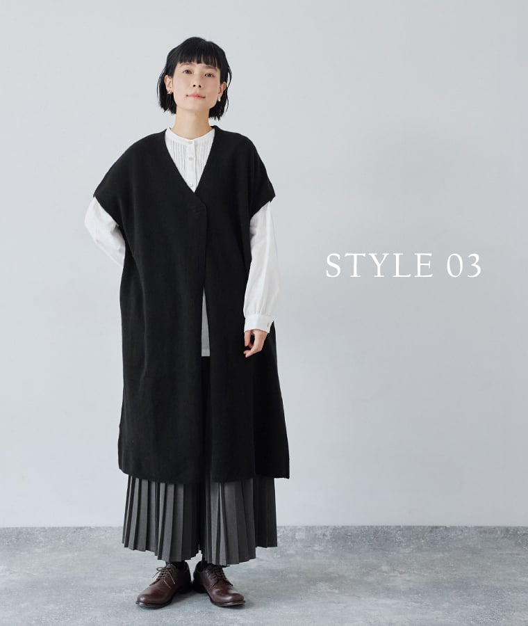 Vネックのブラックロングベストと白シャツのすっきりとした重ね着