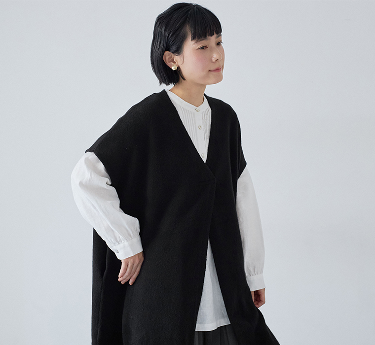 Vネックのブラックロングベストと白シャツのすっきりとした重ね着
