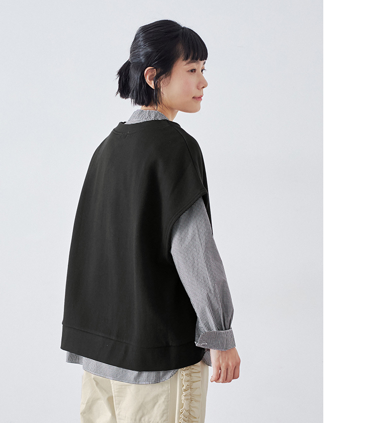 ブラックの裏毛ベストとチェックシャツ、フリルパンツを合わせたコーディネート（斜め後ろからの立ち姿）