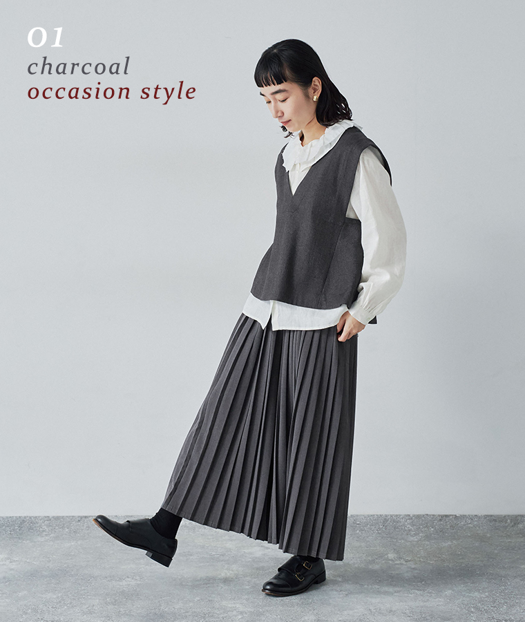 別注｜プリーツパンツのチャコールを着用したモデルが白いブラウスとベストを合わせて立っている