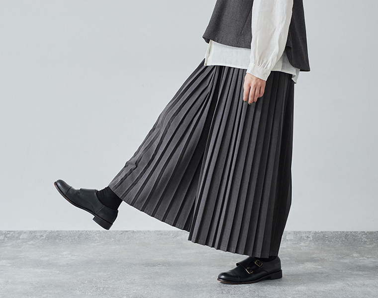 別注｜プリーツパンツのチャコールを着用したモデルが歩いている足元