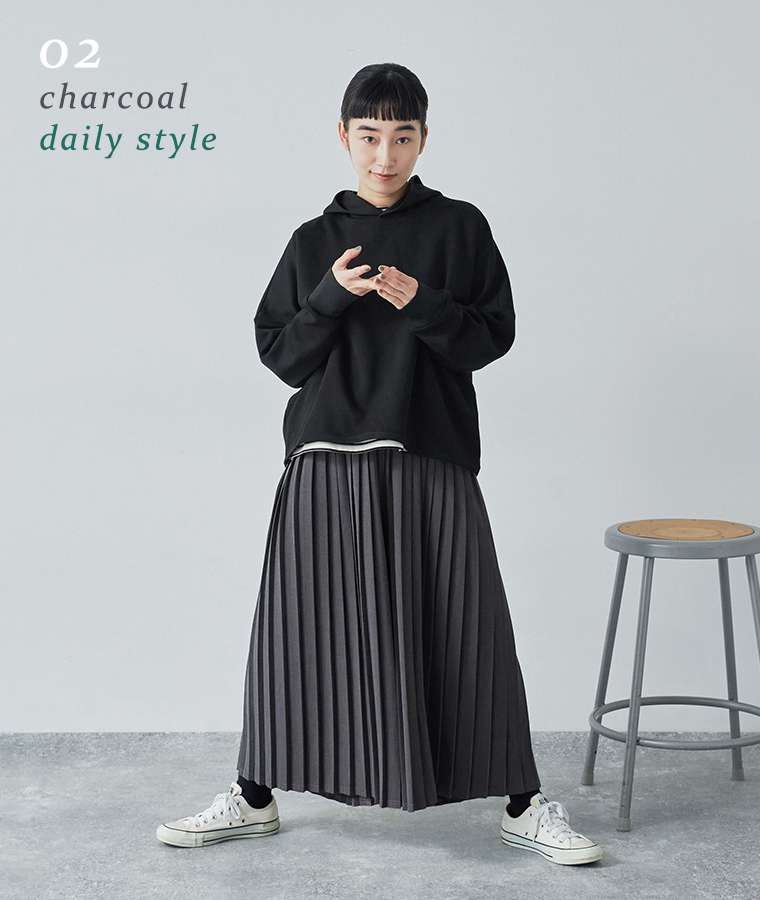 別注｜プリーツパンツのチャコールを着用したモデルがフーディーと合わせて立っている