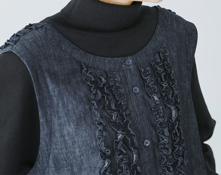 コットンリネンループ染めインディゴ前後フリル使い2wayノースリーブワンピースのインディゴを黒のタートルネックの上に重ねて前身頃のフリルとボタンが見える状態で着用している上半身のクローズアップ