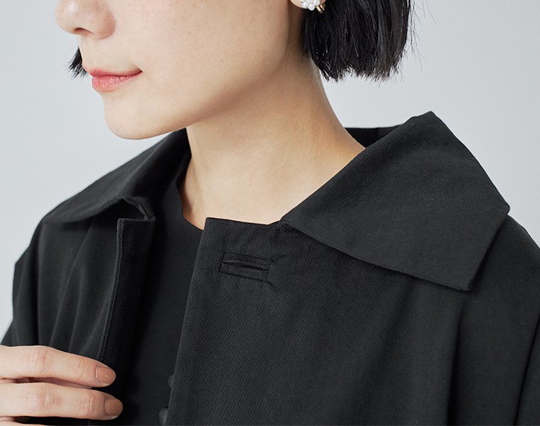 首元にやさしく沿うステンカラーが上品な、ブラックのロングコートの襟元デザイン
