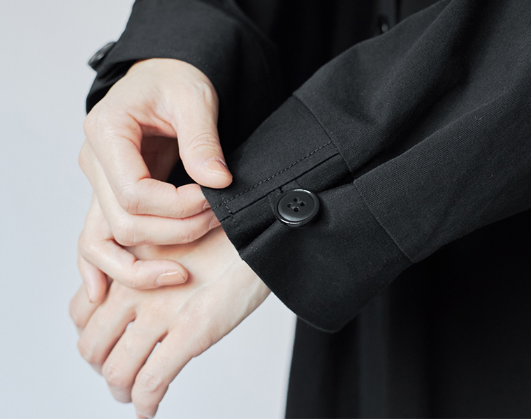 袖口のボタン仕様がさりげないアクセントになる、ブラックのロングステンカラーコート