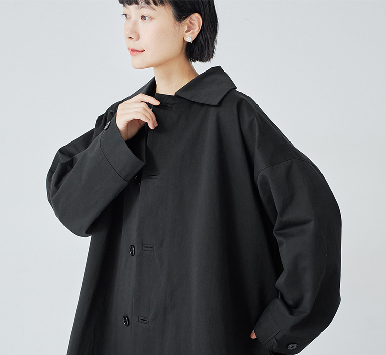 ゆったりとした身幅とステンカラーが特徴の、ブラックのロングコート着用イメージ