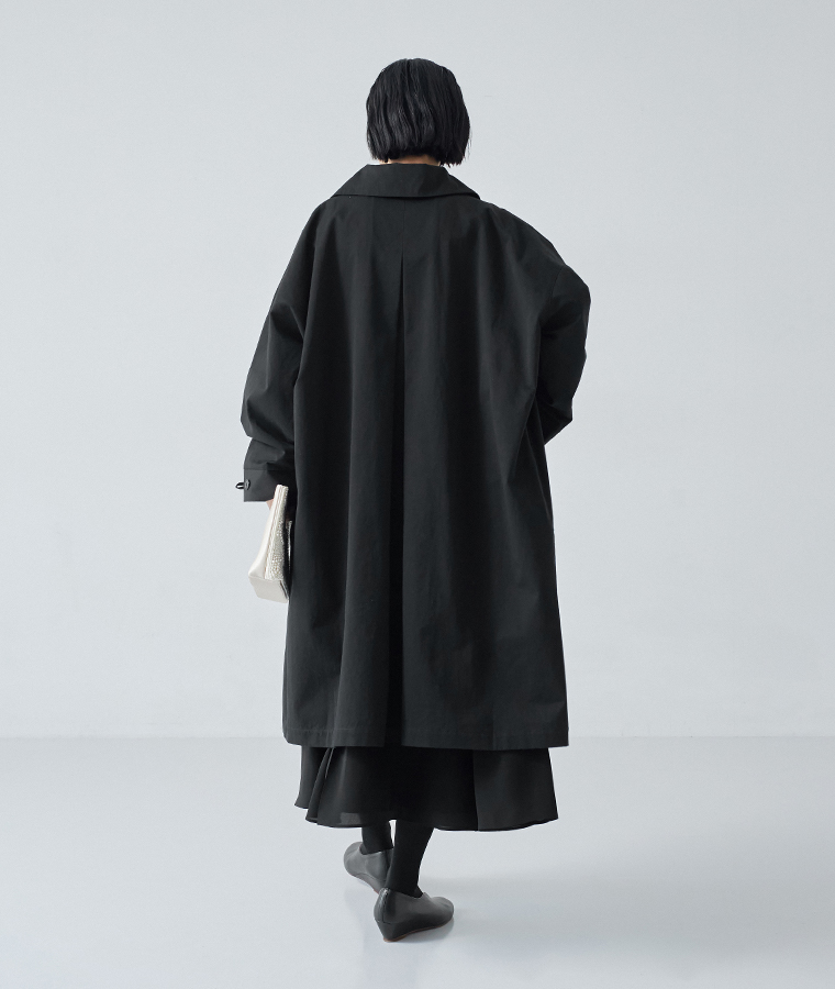 ゆとりのあるシルエットで重ね着しやすい、ブラックのロングステンカラーコート後ろ姿