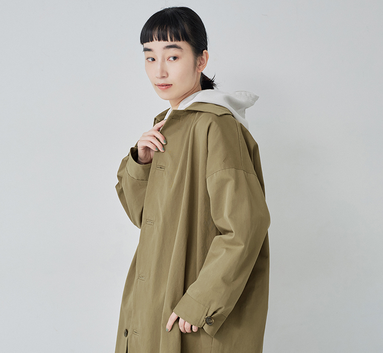 ゆったりとした身幅が魅力の、ダークベージュのロングステンカラーコート着用イメージ