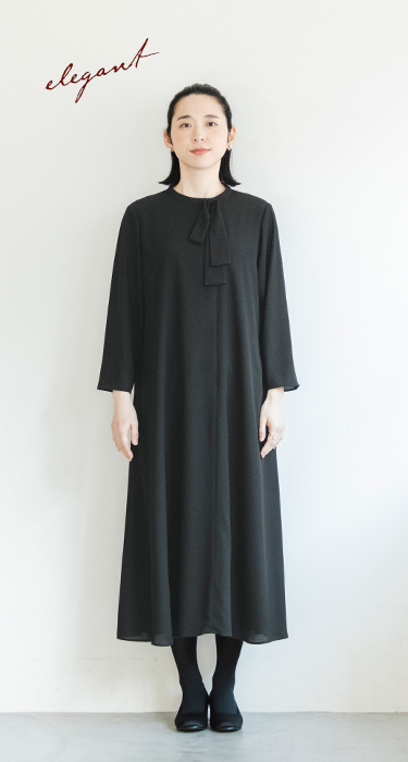 黒のボウタイ付きAラインワンピースを着た人物の正面コーディネート