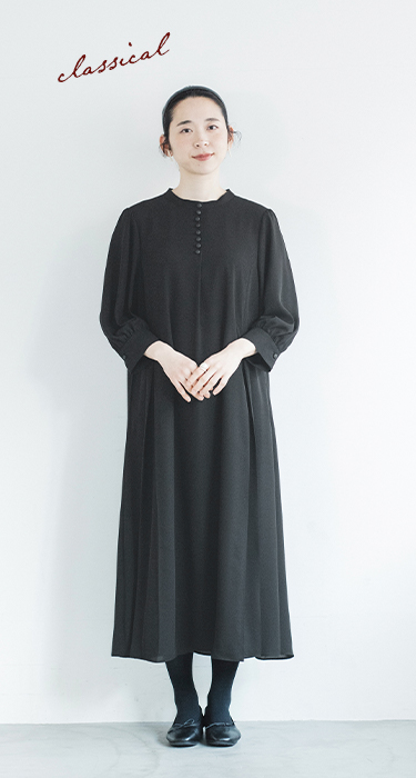 黒のボタンフレアワンピースを着た人物の正面コーディネート