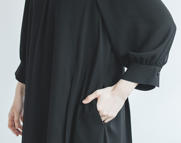 黒のワンピースのポケットに手を入れた人物の袖とポケットのディテール