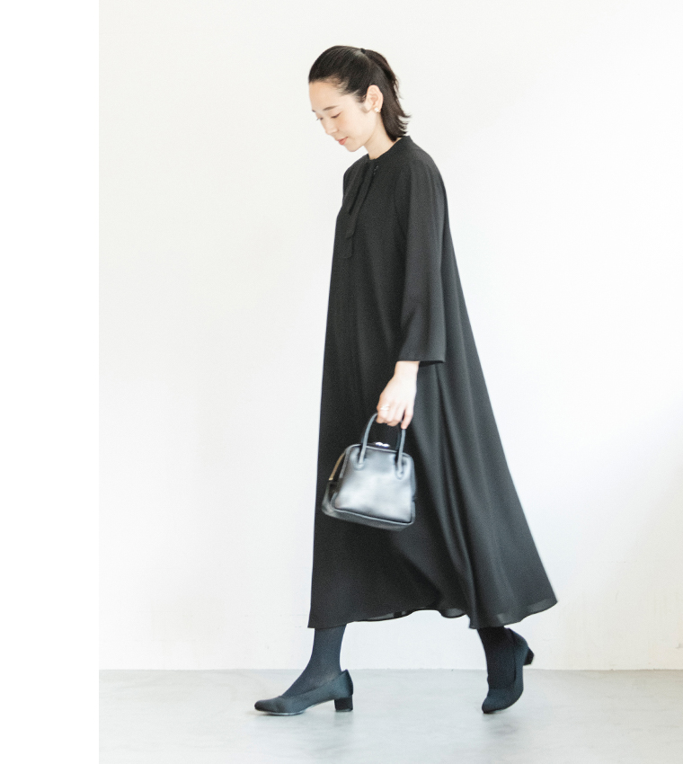 黒のボウタイ付きワンピースを着た人物が歩いている横向きのコーディネート