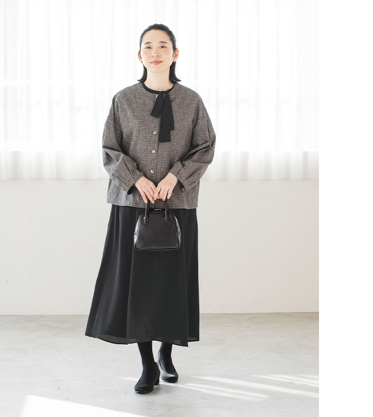 黒のボウタイ付きワンピースにジャケットを羽織ったコーディネート