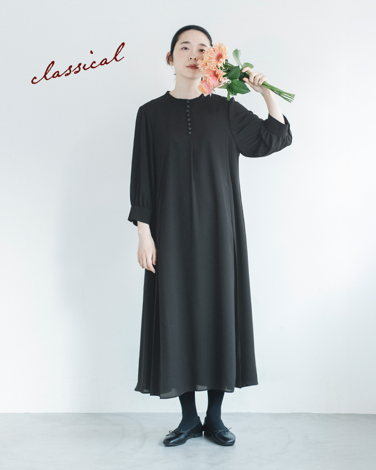 黒のボタン付きワンピースを着た人物が花束を顔に近づけて持つコーディネートカット