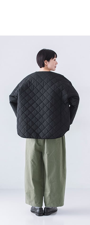 キルティングジャケットとモスグリーンパンツの後ろ姿、ゆったりとしたシルエット