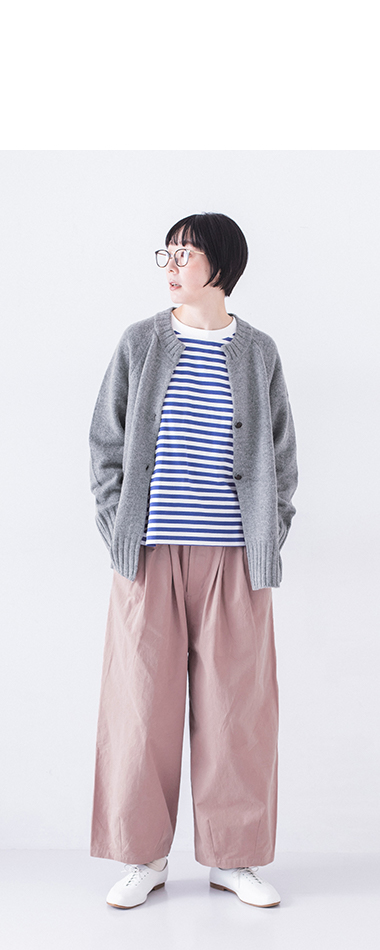 グレーカーディガンとピンクパンツを着た人物のリラックスした立ち姿、カジュアルな日常コーディネート