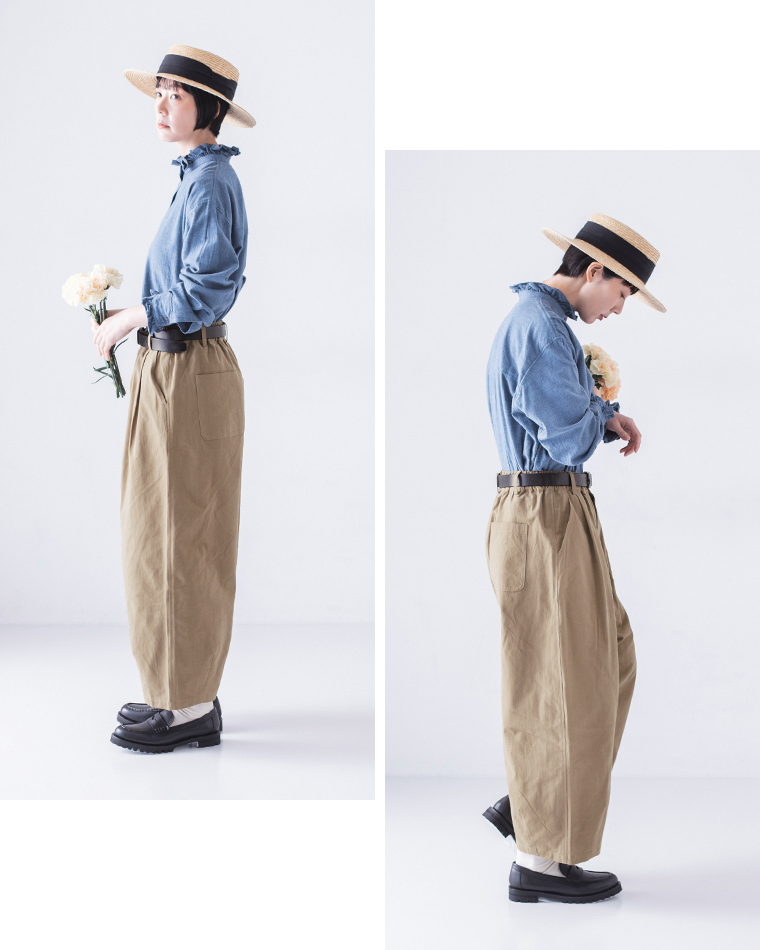 ベージュパンツの後ろポケットに花を挿した後ろ姿、ブルーシャツとのナチュラルなコーディネート