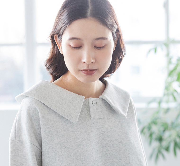 室内でエクリュのプルオーバーを着た人物の上半身ポートレート（自然光と観葉植物のある背景）