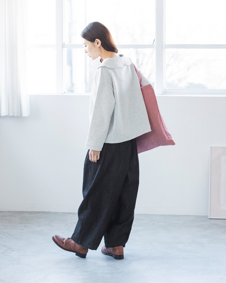 エクリュのプルオーバーとデニムパンツのコーディネート（ピンク×白のストライプ柄トートバッグ・ミニマルな室内）