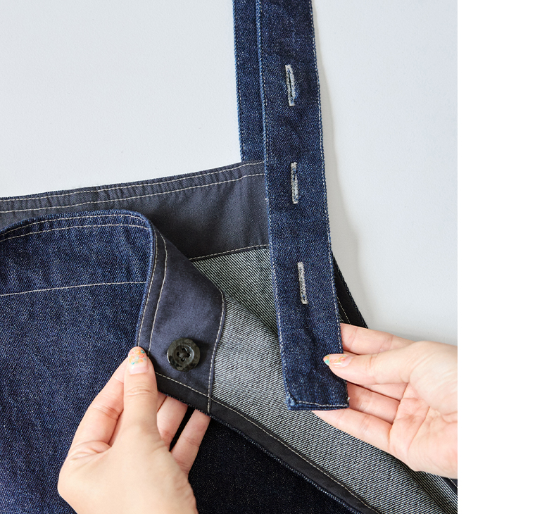 デニムオーバーオールのストラップ部分のボタン調整ディテール