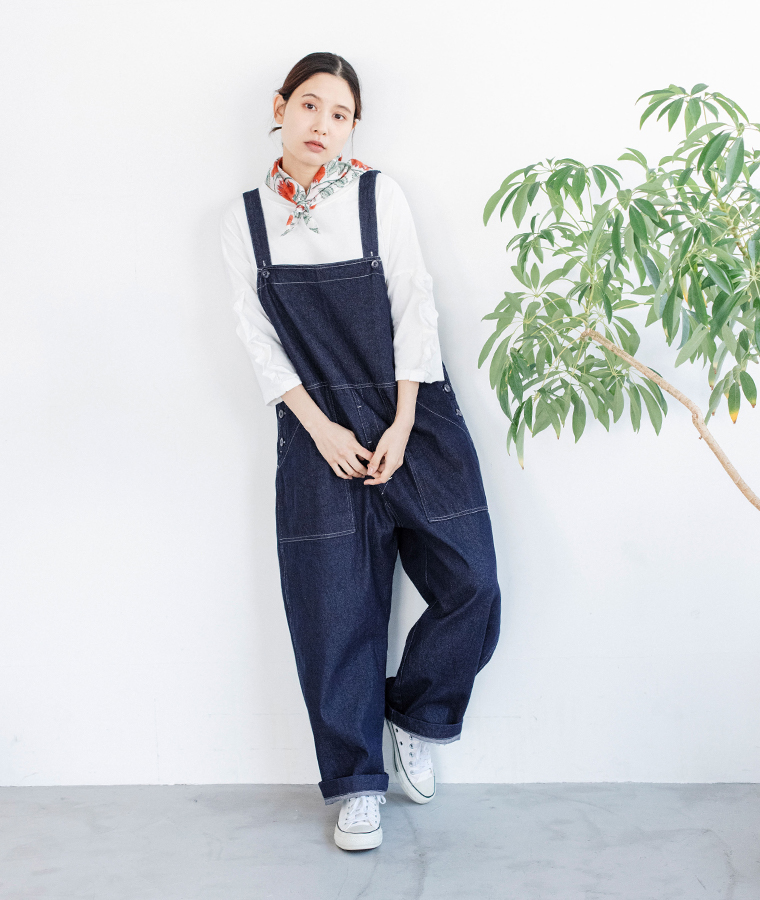 デニムオーバーオールを白のカットソーとスカーフに合わせたサイド寄りの立ち姿コーディネート
