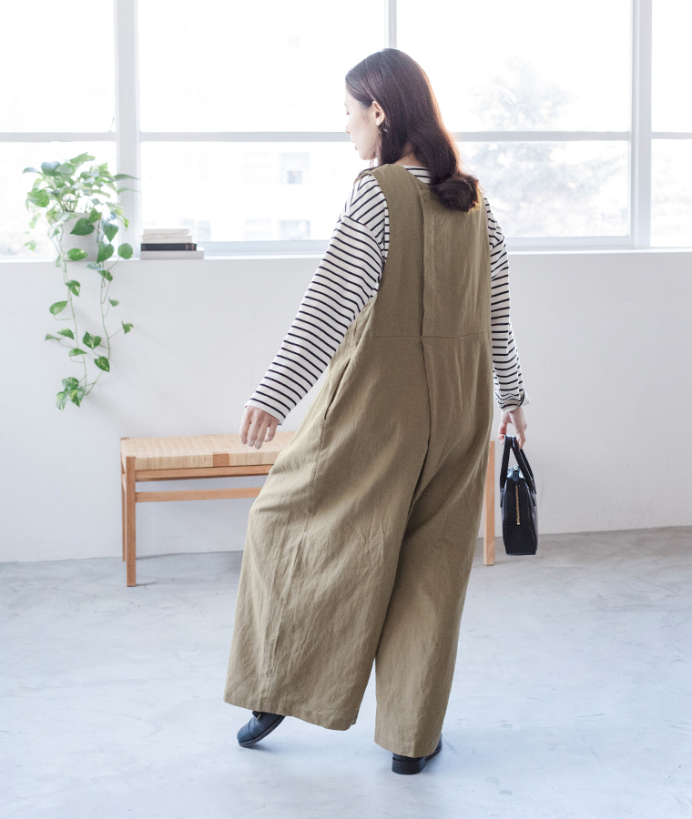 リネンコットン2wayサロペットを着た後ろ姿のコーディネート（室内・観葉植物あり）