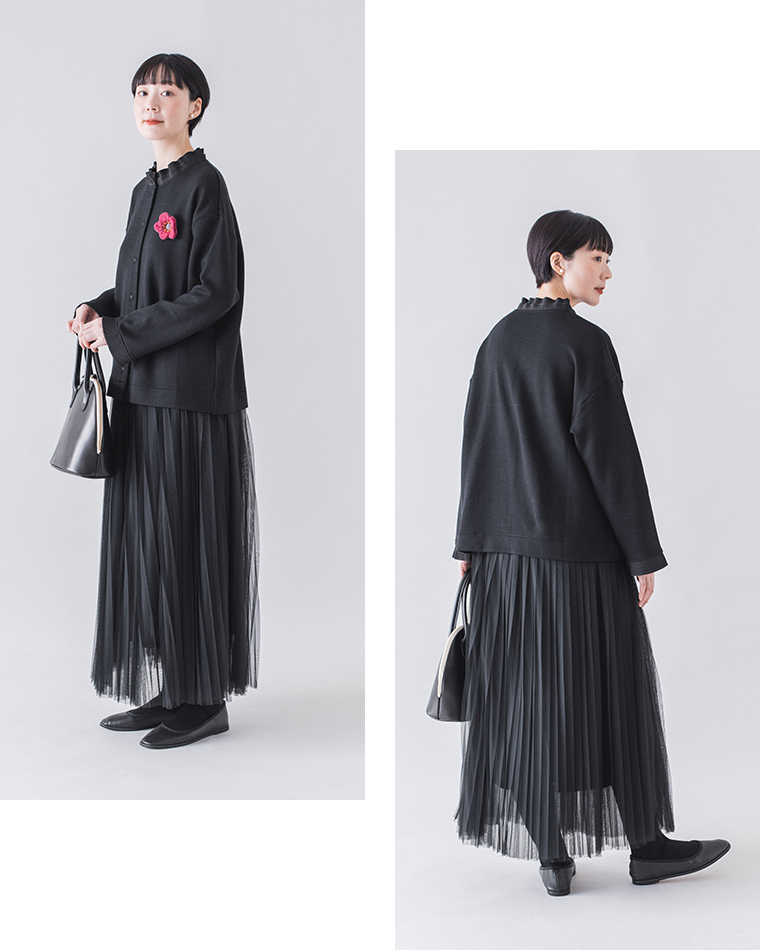 ブラックのカーディガンとプリーツスカートの前後スタイル比較（ピンクの花ブローチと白ハンドルのバッグ付き）