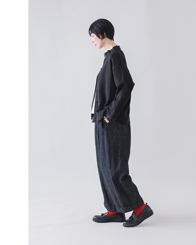 ブラックのカーディガンとダークデニムパンツを合わせた横向きコーディネート（赤い靴下がアクセント）