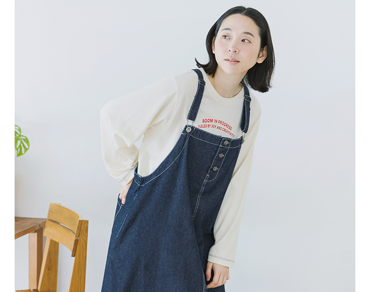 ワークジャンパースカート着用の上半身を前寄りで写し肩ひもと前ボタンが見える