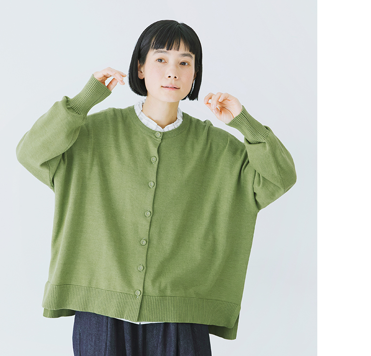 グリーンのカーディガンを白ブラウスとパンツに合わせたコーディネート（上半身寄り）