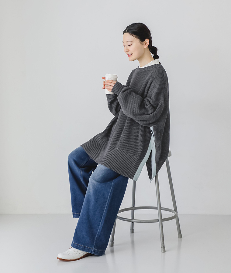 畦編みニット配色スリットプルオーバーを着用したモデルの全身座りカット