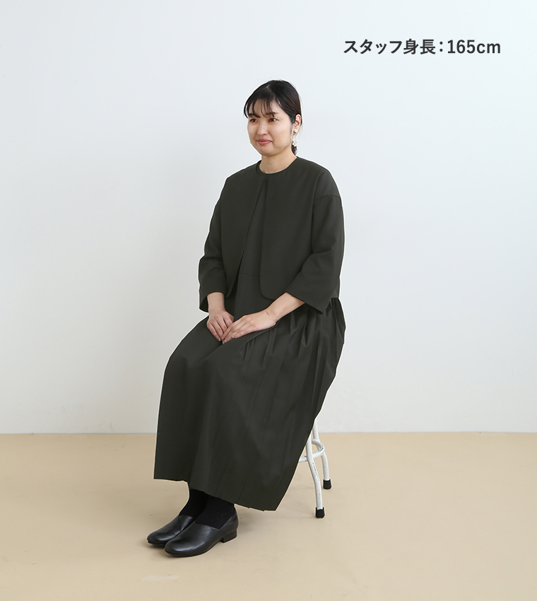 スタッフ身長165cmがジャケットプリーツアンサンブル（ブラックLサイズ）を着用し座ったカット