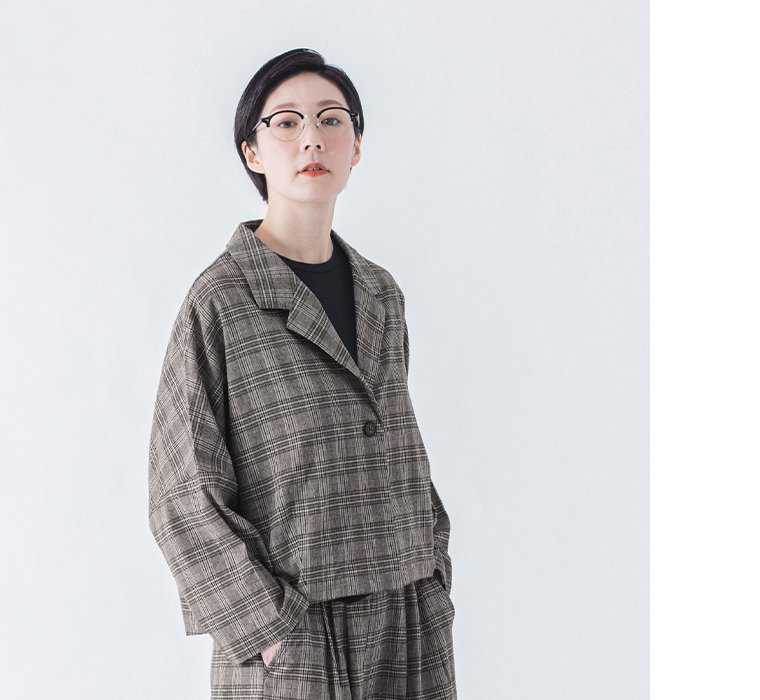 チェックのショートテーラードジャケットとタックワイドパンツを着た斜め正面上半身寄りコーディネート
