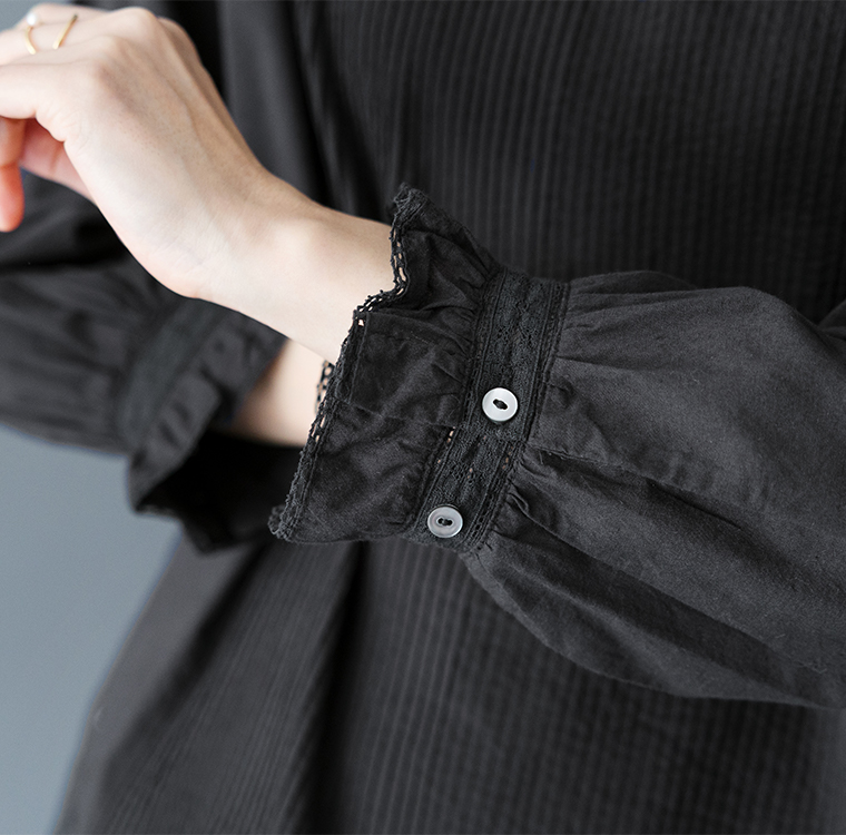 ブラックブラウスの袖口ディテール（レースとボタン付き）
