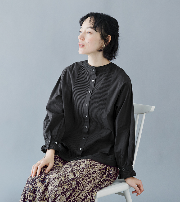 ブラックブラウスと柄スカートを着用した座りスタイル（ピンタックとホワイトボタン付き）