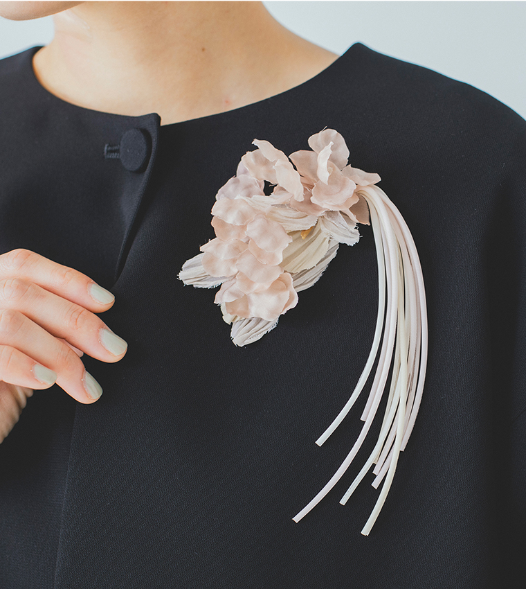 黒いジャケットに淡いピンクの布花コサージュを合わせた胸元の着用イメージ