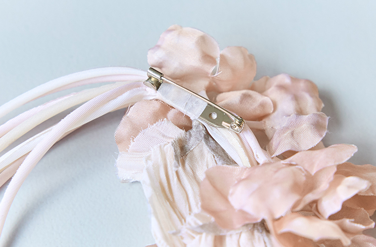 淡いピンクの布花コサージュの裏側と金具パーツを写したディテール画像