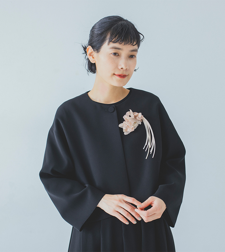 黒いフォーマルウェアに淡いピンクの布花コサージュを合わせた上半身の着用イメージ