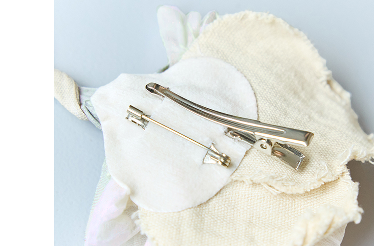 クリーム系の布花コサージュ裏側に付いたクリップとピン仕様を写したディテール画像