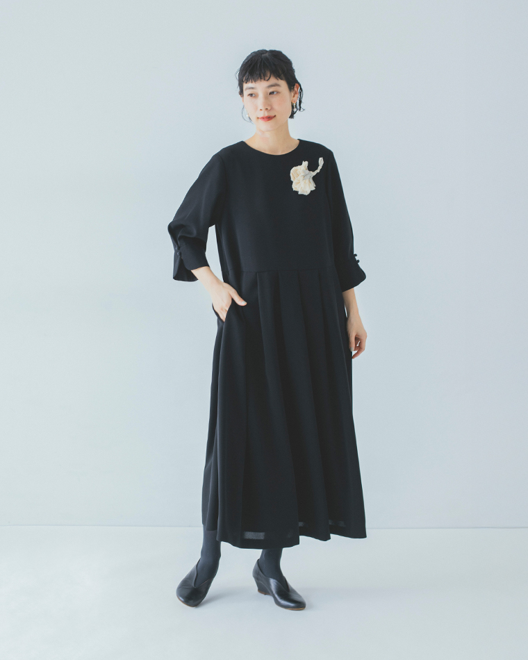 黒いワンピースに白系コサージュを合わせた全身コーディネート