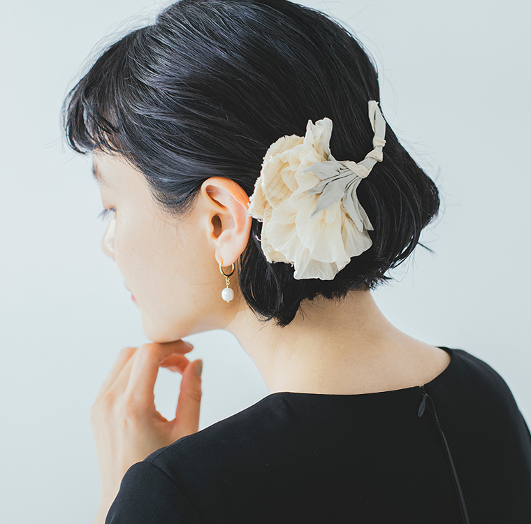 淡いクリーム系の布花コサージュを髪に合わせた後ろ姿の着用イメージ