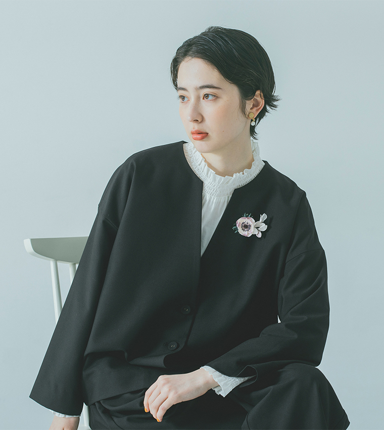 黒いジャケットに布花コサージュを合わせた着席モデルの上半身カット