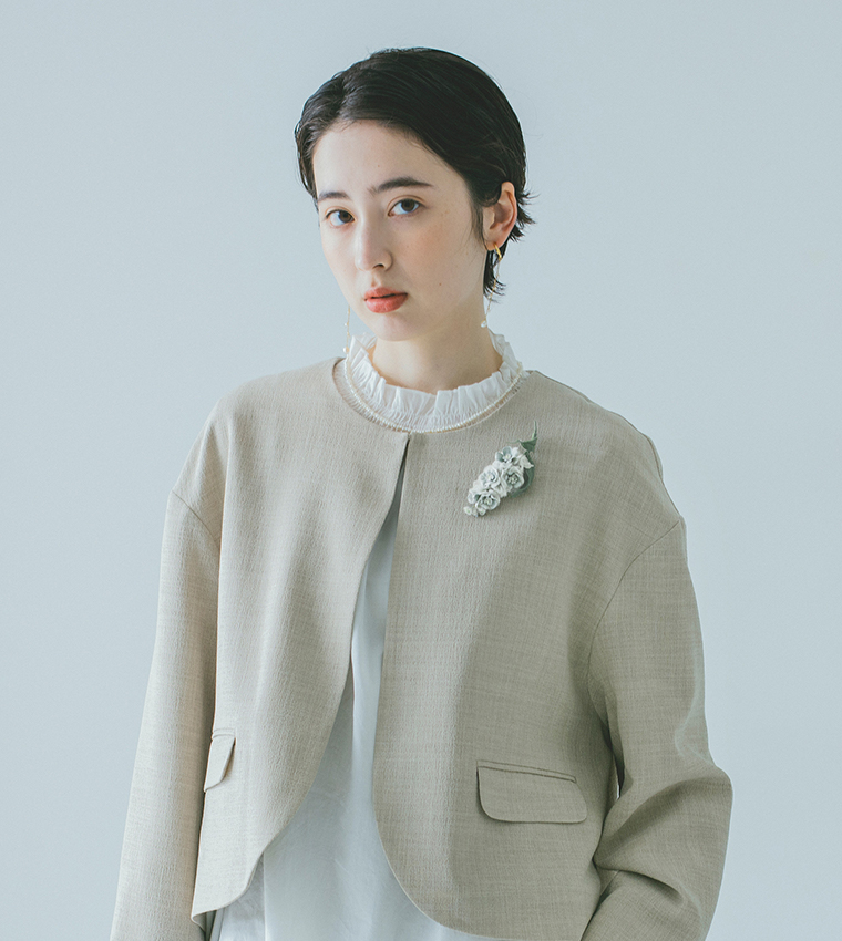 ライトベージュのジャケットに白系コサージュを合わせたモデル着用カット