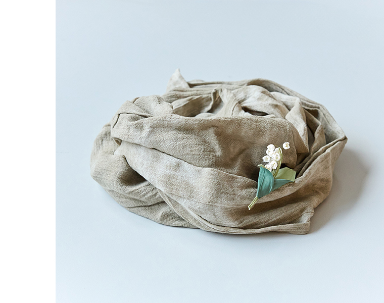 ベージュのスカーフに白い花材を添えた柔らかな雰囲気のスタイリングカット