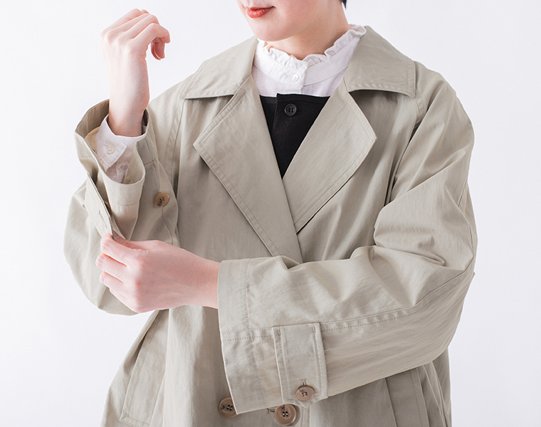 コットンナイロン ダブルボタンジャケットのライトベージュを着用し袖口のボタンを留めている手元のアップカット
