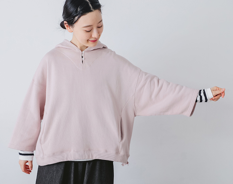 コットンガーゼ裏毛ドロストフーディを着用したモデルが腕を広げて袖丈と身幅を確認できるカット