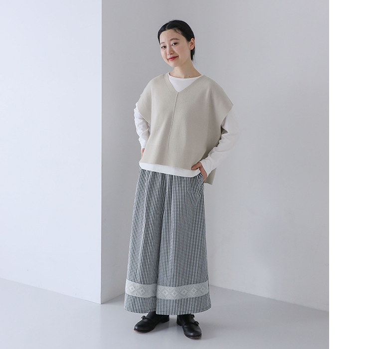 レース付きワイドパンツを着用しベージュのニットベストと白インナーを合わせた全身コーディネート