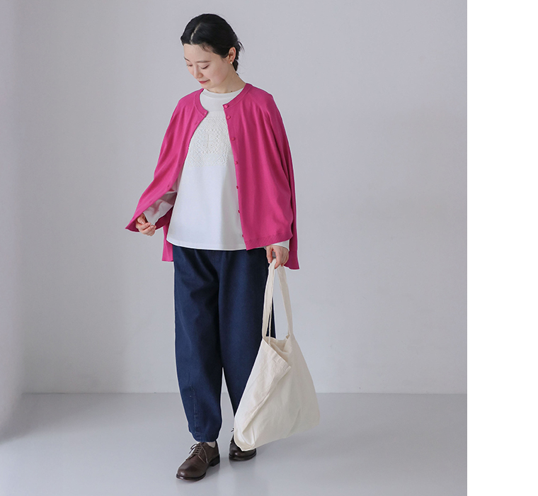 モチーフレースプルオーバーを着てピンクのカーディガンとデニムパンツを合わせトートバッグを持って歩くコーディネート